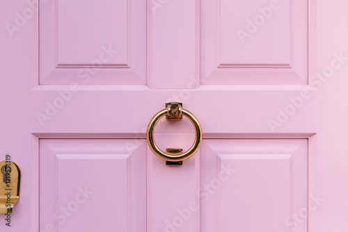 Golden knocker on pink door creating elegant contrast