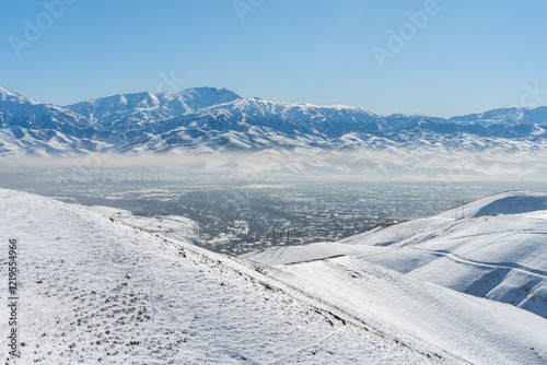 Uzbek city Angren from the mountains in Chatkal Range in Winter under clear blue sky. photo