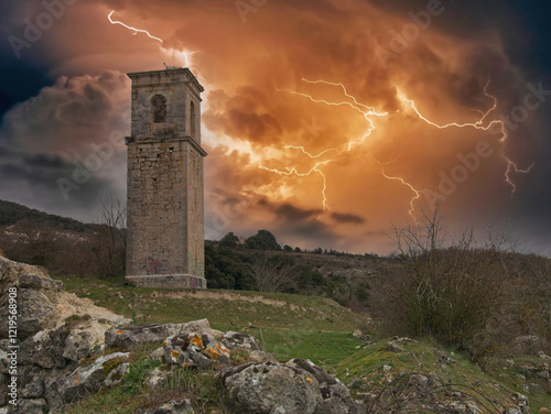 Church tower of haunted village Ochate with a firy thunderstorm and lightings in the sky, in Treviño, Burgos, Spain