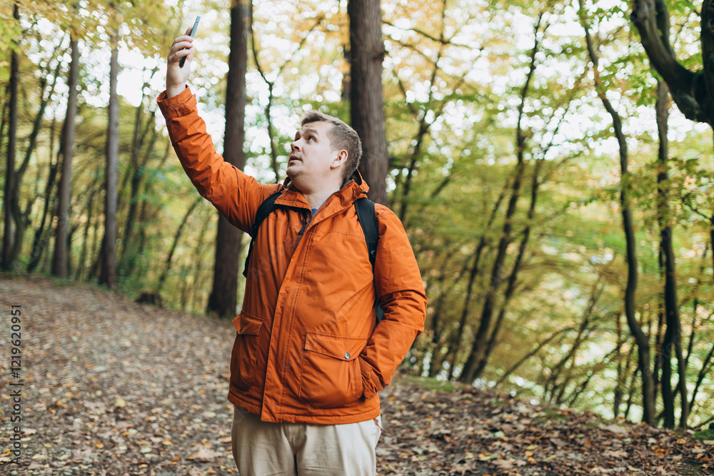Sad angry blonde man got lost and could not find an internet connection on phone while hiking alone in the forest. Road trip, transport, travel, technology and people concept. High quality photo