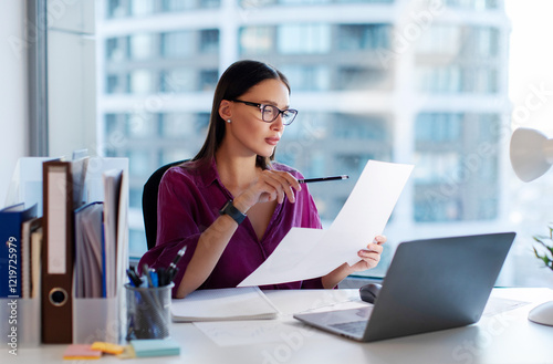 Young lady manager accountant analyst checking bills, analyzing sales statistics management, financial data documents or marketing report papers in office