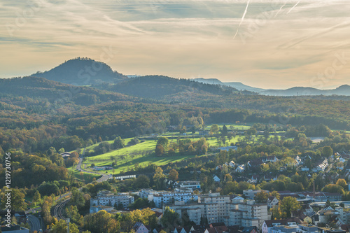 Ausblick auf Hügelkette der schwäbischen Alb mit Berg Achalm und Sonnenschein auf grüne Wiese hinter Ortschaft Metzingen photo