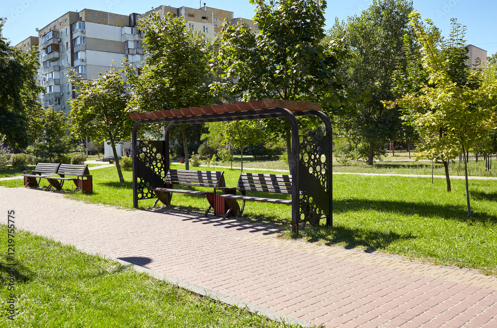 Rest area with benches surrounded by trees and ornamental shrubs in Kyiv, Europe. Place to rest in the city park at summer Rest area with benches surrounded by trees and ornamental shrubs in Kyiv, Europe. Place to rest in the city park at summer