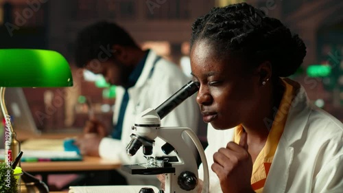 Wallpaper Mural Female science student examines cells under the microscope for her scientific research in a campus library, takes notes about chemical processes and reactions for her thesis. Camera B. Torontodigital.ca