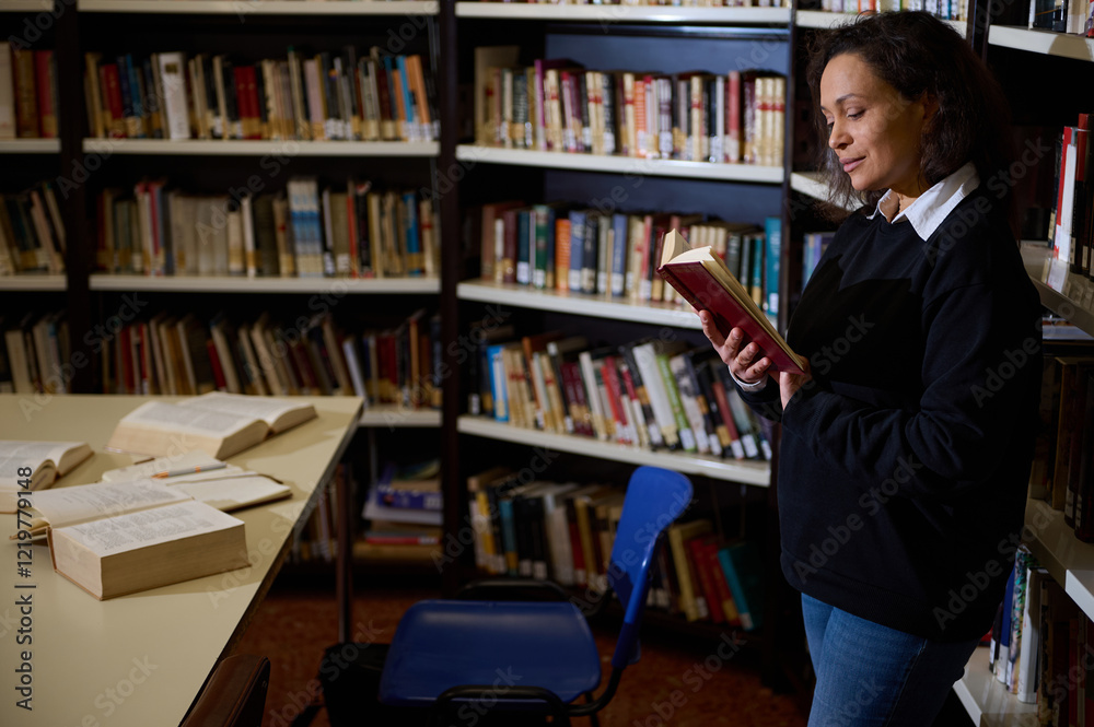 A woman enjoys reading a book while standing in a library filled with shelves of books. Open books are spread across a table nearby, portraying a serene and studious environment. A woman enjoys reading a book while standing in a library filled with shelves of books. Open books are spread across a table nearby, portraying a serene and studious environment.