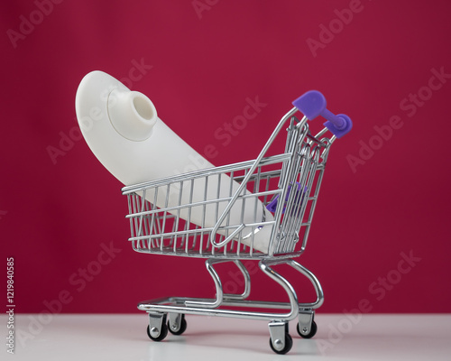 Clitoral vibrator in miniature shopping cart on pink background.  photo