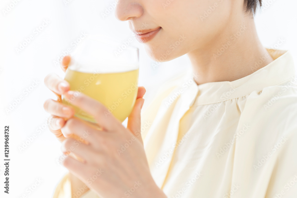 グラスに入った飲み物を飲んでいるミドル世代の女性。 グラスに入った飲み物を飲んでいるミドル世代の女性。
