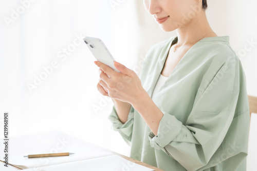 スマートフォンの画面を見ているミドル世代の女性。
