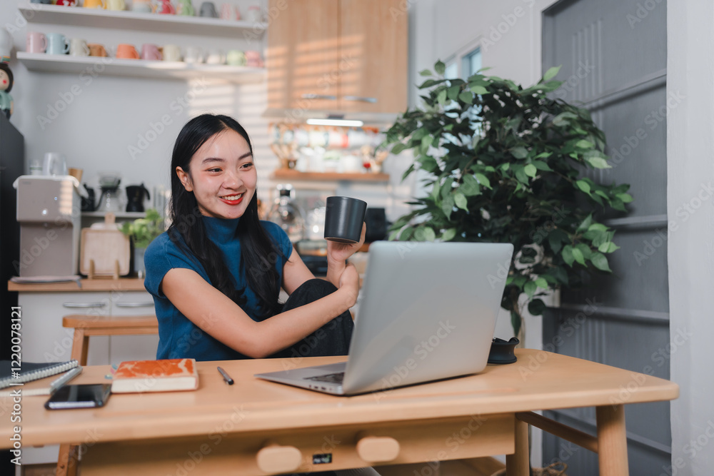 woman smiling while working on laptop at wooden desk in cozy home office woman smiling while working on laptop at wooden desk in cozy home office