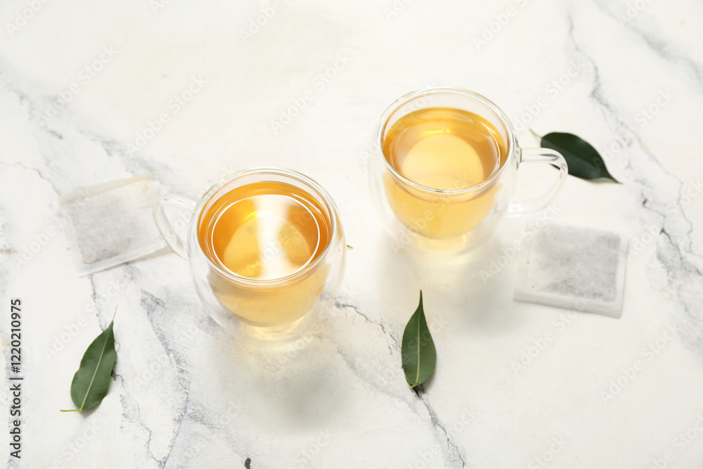Glass cups of hot green tea and leaves on white background Glass cups of hot green tea and leaves on white background