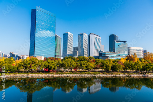 Autumn cityscape of Osaka city skyline with skyscraper building and autumn leaves tree nature park.
