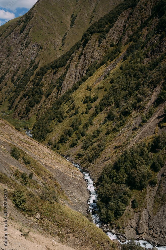 A turbulent mountain river in the gorge of the mountains of the North Caucasus in Georgia. Summer mountain landscape. A mountain river among the mountains. The gorge is high in the mountains A turbulent mountain river in the gorge of the mountains of the North Caucasus in Georgia. Summer mountain landscape. A mountain river among the mountains. The gorge is high in the mountains