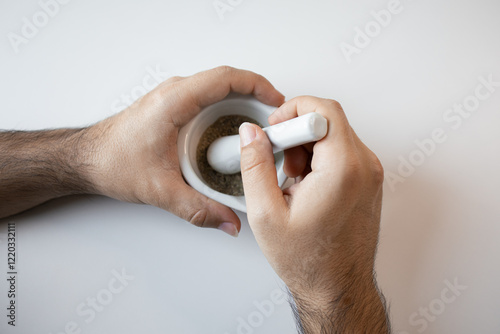 Caucasian male adult crushing spices with mortar and pestle photo