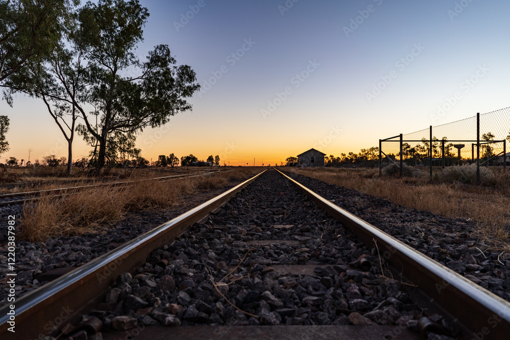 Fototapeta premium Train tracks disappearing into the distant sunrise