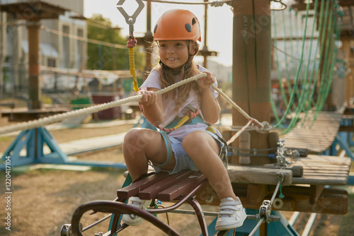 Playful little girl child pulling hawser while overcoming obstacles at rope park