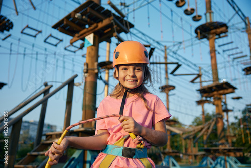 Cheerful little girl child ready to overcome obstacles in rope park photo