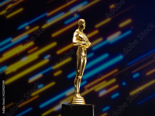 A golden Oscar statue stands on a black base in front of a colorful background
