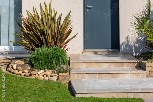 Petit jardin paysagé et ses plantes fleuries au pied d'une maison moderne.