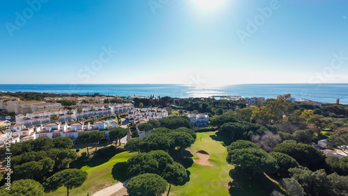 Obraz na płótnie Aerial drone photo of a beautiful golf course in the town of Cabopino in Marbella Costa del Sol Spain with the ocean in the background surrounded by apartments on a hot sunny day w salonie