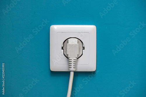 White PC plug is plugged into a white socket on a cyan-painted wall.