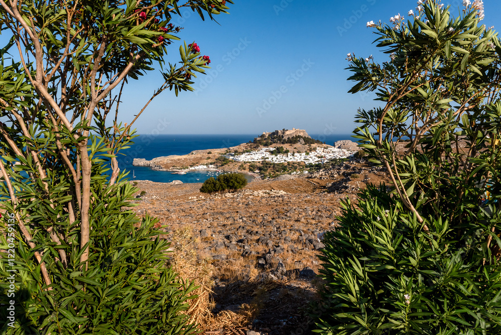 Distant view through shrubbery of Lindos town and ancient acropolis, Rhodes island, Greece Distant view through shrubbery of Lindos town and ancient acropolis, Rhodes island, Greece