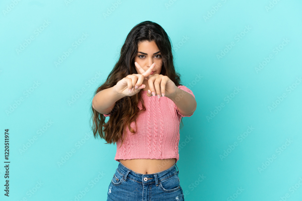 Young caucasian woman isolated on blue background making stop gesture with her hand to stop an act Young caucasian woman isolated on blue background making stop gesture with her hand to stop an act