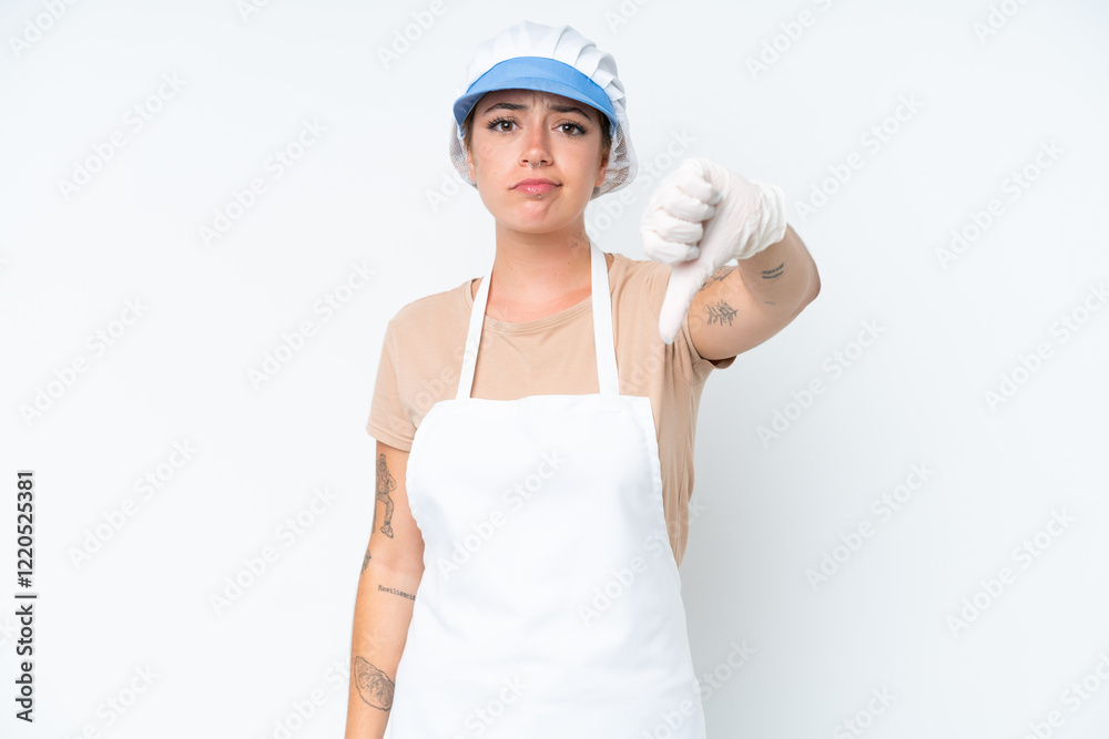 Fishmonger wearing an apron and holding a raw fish isolated on white background showing thumb down with negative expression Fishmonger wearing an apron and holding a raw fish isolated on white background showing thumb down with negative expression