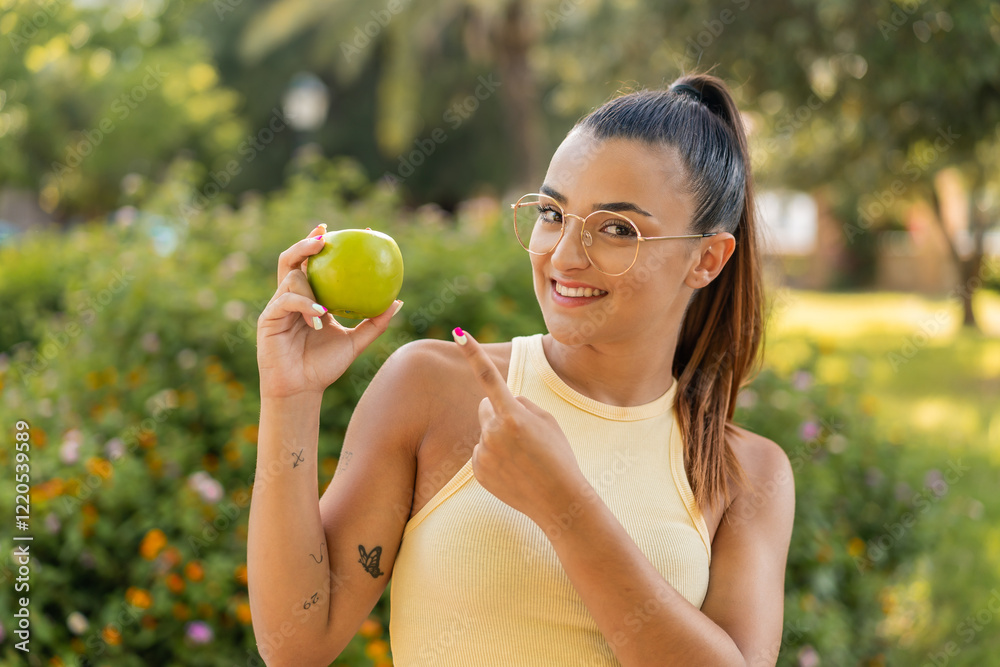 Young pretty woman with an apple at outdoors and pointing it Young pretty woman with an apple at outdoors and pointing it