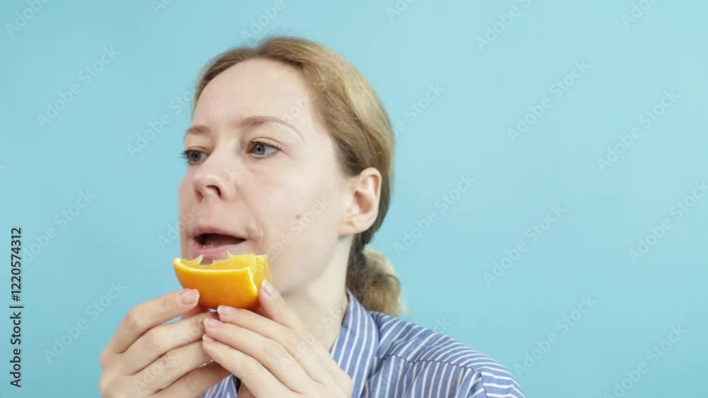 Woman eating an orange, enjoying dessert indoors, health and fresh choices. Woman eating an orange, enjoying dessert indoors, health and fresh choices.