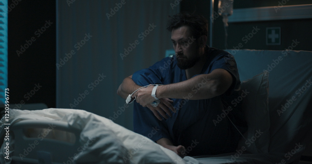 Fototapeta premium Patient sits, holding head, swaying on bed.