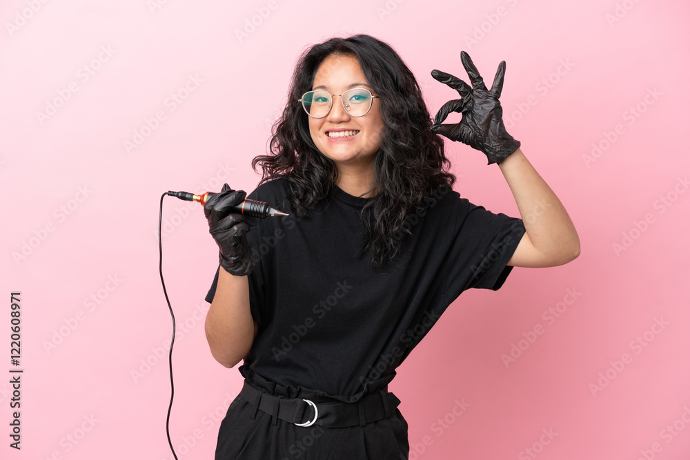 Tattoo artist asian woman isolated on pink background showing ok sign with fingers Tattoo artist asian woman isolated on pink background showing ok sign with fingers