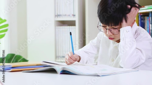 A young student concentrating on his schoolwork and studies, studying hard despite being bored and tired.
 photo