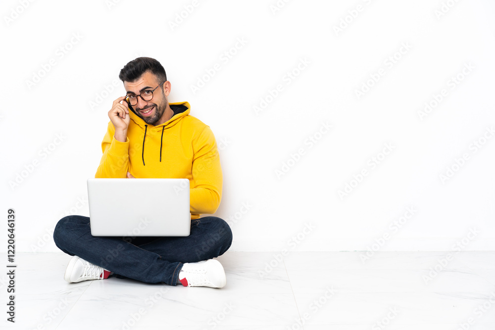 Caucasian man sitting on the floor with his laptop with glasses and happy Caucasian man sitting on the floor with his laptop with glasses and happy