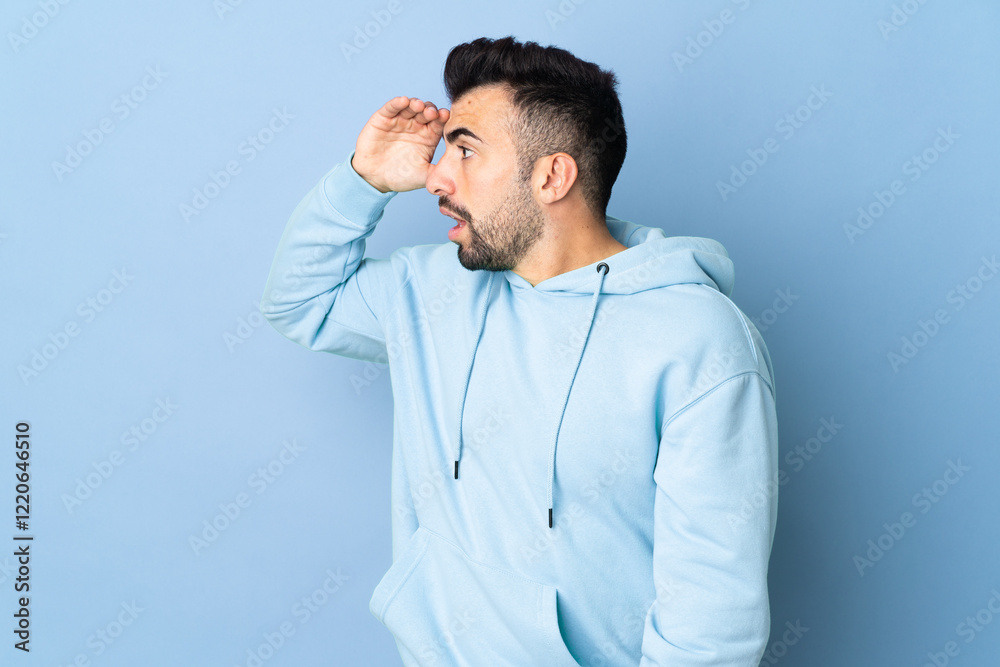 Caucasian man over isolated blue background with surprise expression while looking side Caucasian man over isolated blue background with surprise expression while looking side