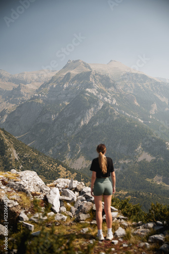 A hiker admires the towering peak of Collarada, surrounded by the rugged beauty of the Pyrenees under a pristine summer sky. photo