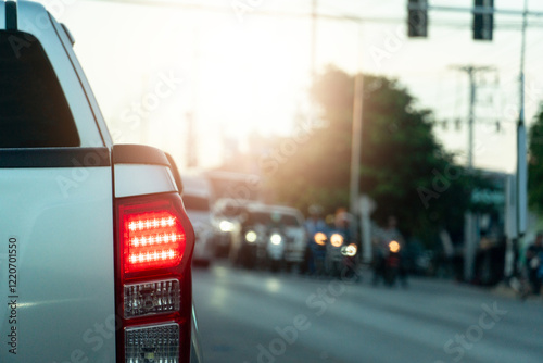 Rear side view of pickup car. Stop and turn on brake light on asphalt road. Stopped at a traffic light and there was a car crossing the road.