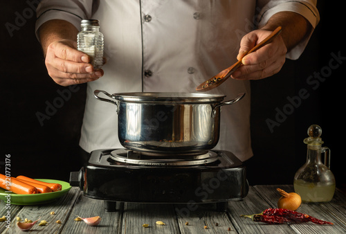 Canvas Print A skilled cook adds spices to a bubbling pot on a stovetop, balancing flavors with precision