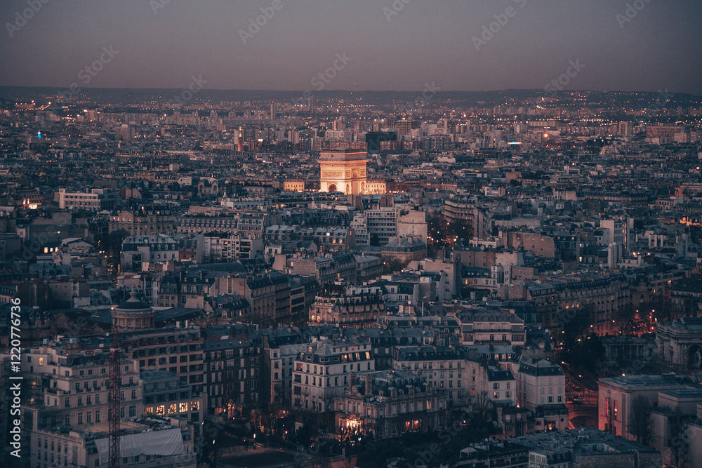 Obraz premium A city skyline of Paris with a tall building in the middle. The sky is dark and the city is lit up