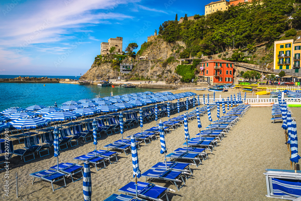 Beautiful beach with striped parasols in row, Cinque Terre, Italy