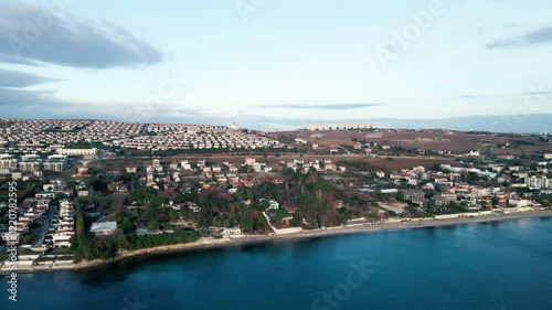 Drone flying over sea water with coastal district at sunset with clear sky in the village of Guzelce photo