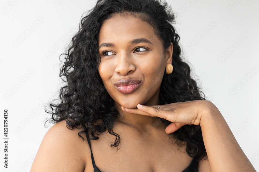 Happy good-looking black plus size female with curly hair putting hand under chin and pouting lips like asking to check her look and make up out before going to date or party, isolated on white Happy good-looking black plus size female with curly hair putting hand under chin and pouting lips like asking to check her look and make up out before going to date or party, isolated on white