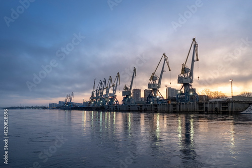 A beautiful industrial seaport or river port at dawn with cranes and calm waters. Cargo transportation shipping and logistics photo