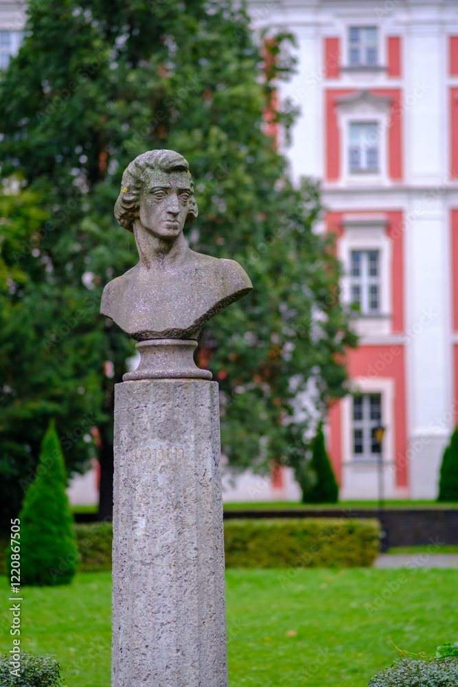 Obraz premium A Chopin's statue on a pedestal in a park before a building