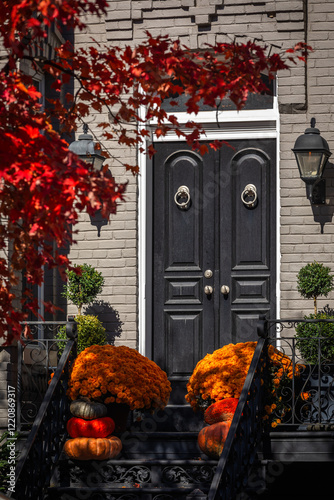 Festive Halloween Decoration with orange Pumpkins and Flowers at the Entrance Door with Staircase to a Single-Family Home photo