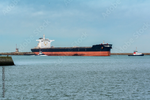 Remorqueurs entrain de faire pivoter un grand navire de commerce à la sortie du port de Dunkerque