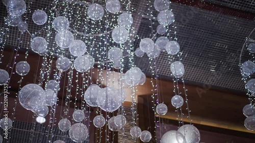 Close-up of shimmering festive decoration featuring translucent spheres and twinkling lights, creating a magical and elegant ambiance suitable for holiday celebrations photo