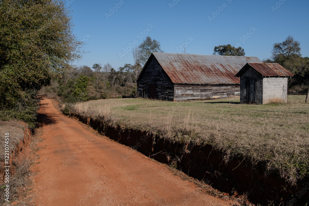 Obraz premium old barn beside a red dirt road in the country