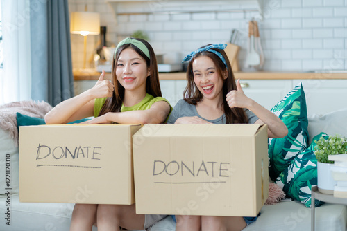 girl friend sitting pack object,putting on stuff into donate box with second hand clothes at home,Recycling,Donation for poor,asian young woman,charity helping and needy people. Reuse recycle,moving. photo