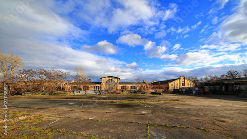 Abandoned industrial buildings surrounded by open concrete space and vibrant blue sky