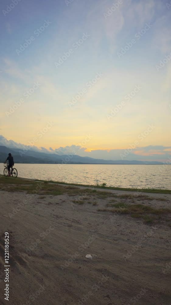 Cyclist on the shore of the lake at sunset in summer Cyclist on the shore of the lake at sunset in summer